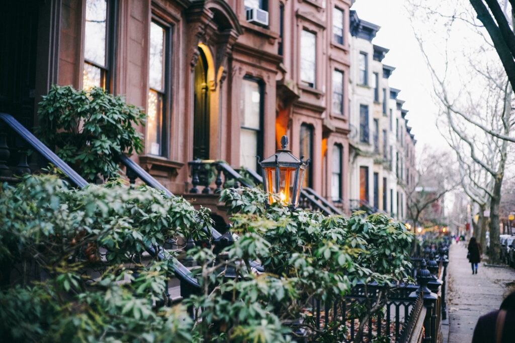 View of New York Brownstones Real Estate on a rainy day with people walking by on sidewalk